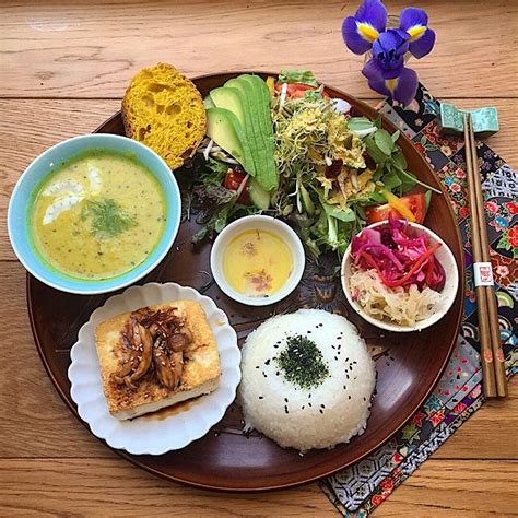 an assortment of food on a plate with chopsticks next to it and flowers