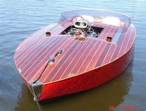 a small wooden boat in the water with its engine on it's back end