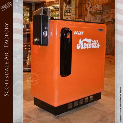 an orange soda machine sitting inside of a store