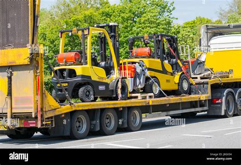 Flatbed truck transporting new forklift trucks Stock Photo - Alamy