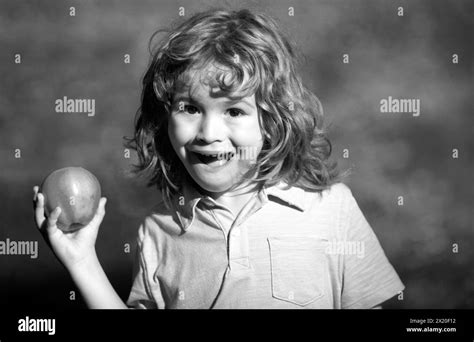 Portrait of little boy holding and eating an apple over green nature background Stock Photo - Alamy