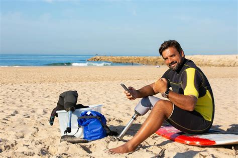 Content ethnic amputee male surfer using smartphone on beach · Free ...