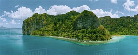 Aerial panoramic drone view of uninhabited tropical island with towering mountains and ...