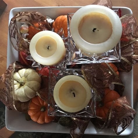 three votive candles sitting on top of leaves and pumpkins