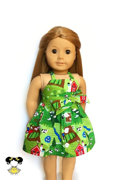 a doll is wearing a green dress with farm animals on it and she has brown hair