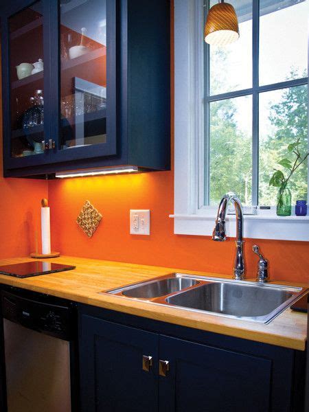 an orange kitchen with black cabinets and stainless steel sink ...