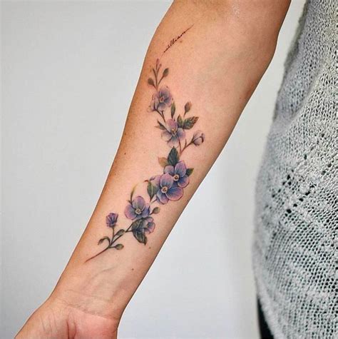 a woman's arm with purple flowers on the left side of her wrist and an ...