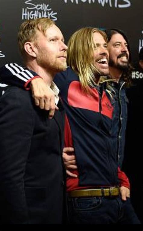 three men standing next to each other on a red carpet