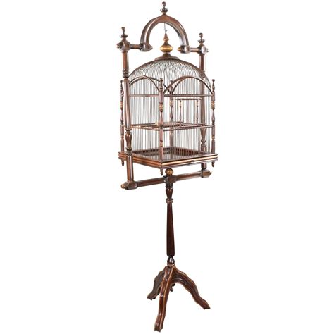 Offered is a large, hanging antique mahogany birdcage with its original wood stand with gilt ...