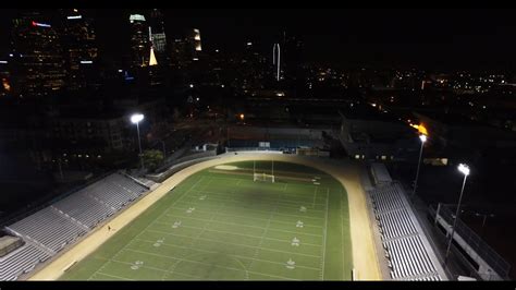 Wide aerial, football field at night in city