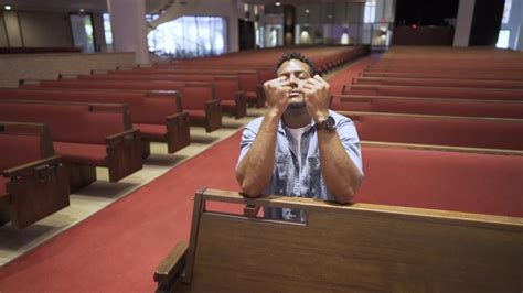 black man on his knees in the pews in a church praying to God - slow motion | ClipStock