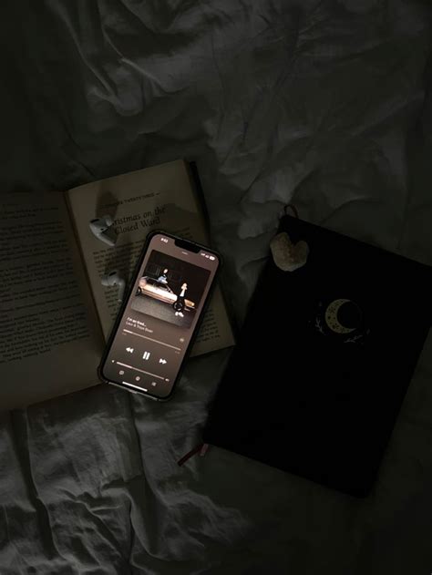 an open book and cell phone on top of a bed next to it's contents