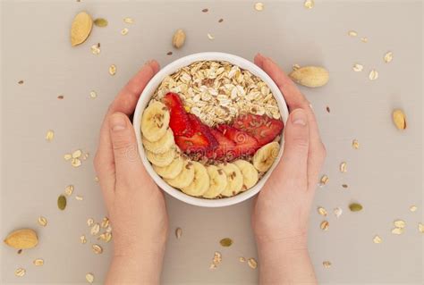 Woman`s Hands Holding Smoothie Bowl with Muesli, Strawberries, Banana Slices and Flax Seed ...