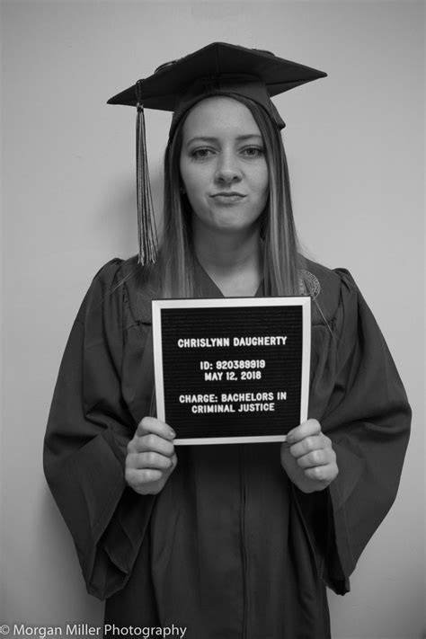 a woman in graduation gown holding up a sign
