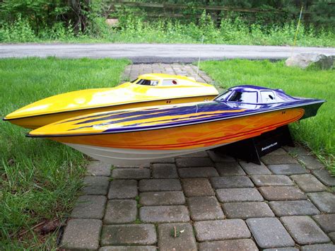 a yellow and blue speed boat sitting on top of a brick walkway in the grass