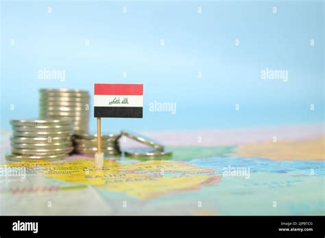 Selective focus of Iraqi flag in blurry world map with coins. Iraq economy and wealth concept ...