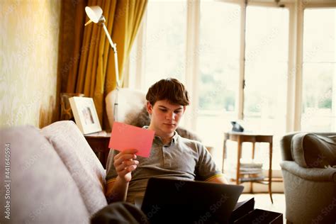 Teenage boy with laptop studying on living room sofa Stock Photo | Adobe Stock