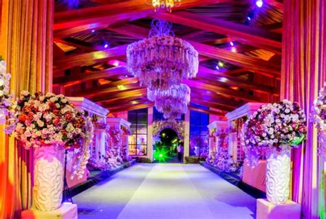 an elaborately decorated hall with chandeliers and flower arrangements on the sidelines