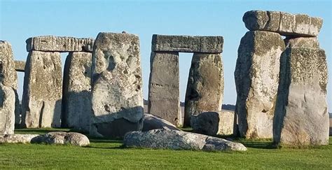 the stonehenge monument in england is surrounded by large rocks and green grass on a sunny day