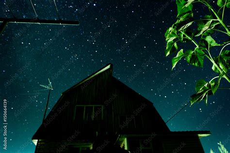 Silhouette of a country house against the background of the starry night sky and the Milky Way ...