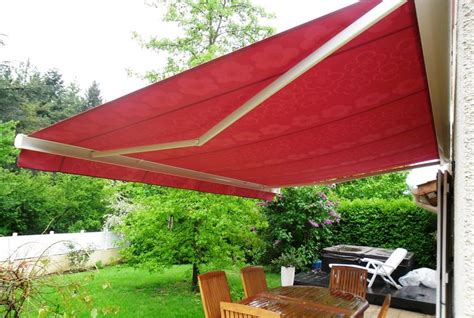 an outdoor dining table and chairs under a red awning over a backyard patio area