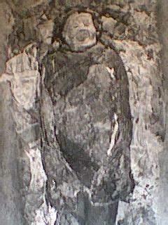 an old photo of a man standing in front of a stone wall with carvings on it