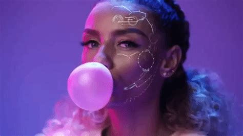 a woman with white face paint blowing a bubble into her mouth and holding a pink balloon in ...