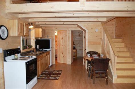 a kitchen and dining area in a log cabin with stairs leading up to the loft