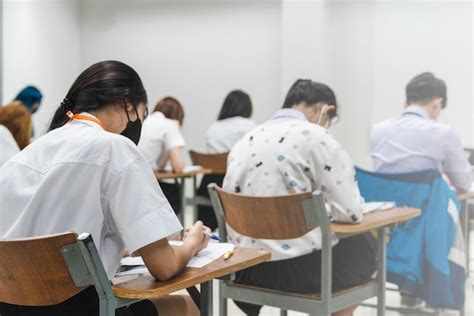 Premium Photo | College students writing on final examination papers in the classroom ...