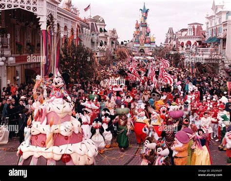 Mickey Mouse (left) pops out of a giant birthday cake, at the front of ...