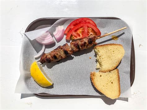 Top view of the national greek dish Souvlaki: Meat skewer with tomatoes, onions, lemon and bread ...