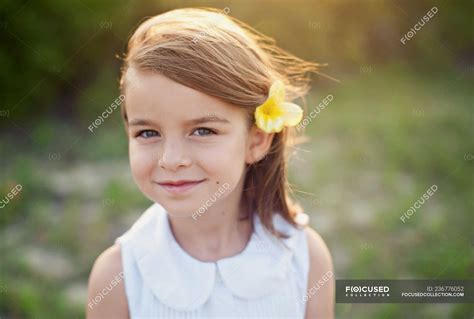 Portrait of a smiling girl with a flower in her hair — nature, windswept - Stock Photo | #236776052