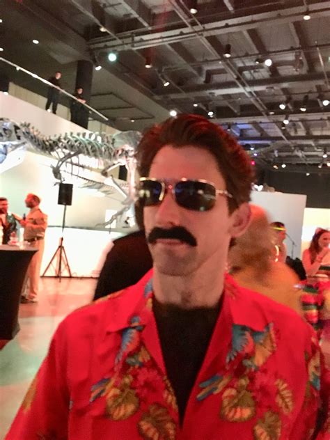 a man wearing sunglasses and a fake moustache stands in front of an exhibit