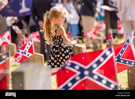 A young girl stands among Confederate flags decorating tombs of ...