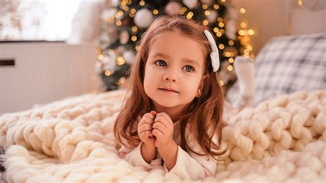 Cute Little Girl Is Lying Down On Bed In Bokeh Christmas Tree ...