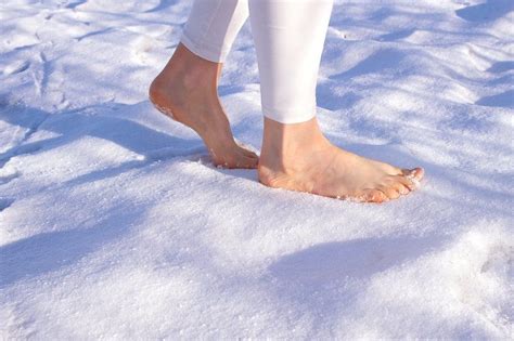 Woman walks barefoot in the snow in winter. Barefoot in the snow in ...