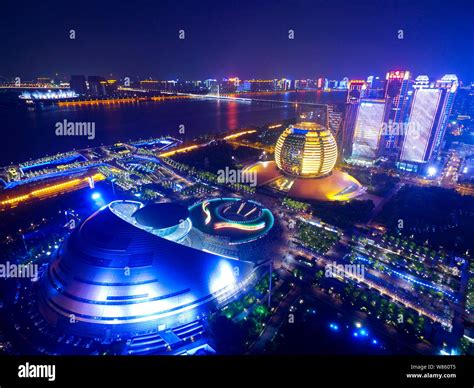 Night view of the Hangzhou Grand Theatre, front, the InterContinental Hotel Hangzhou, in yellow ...