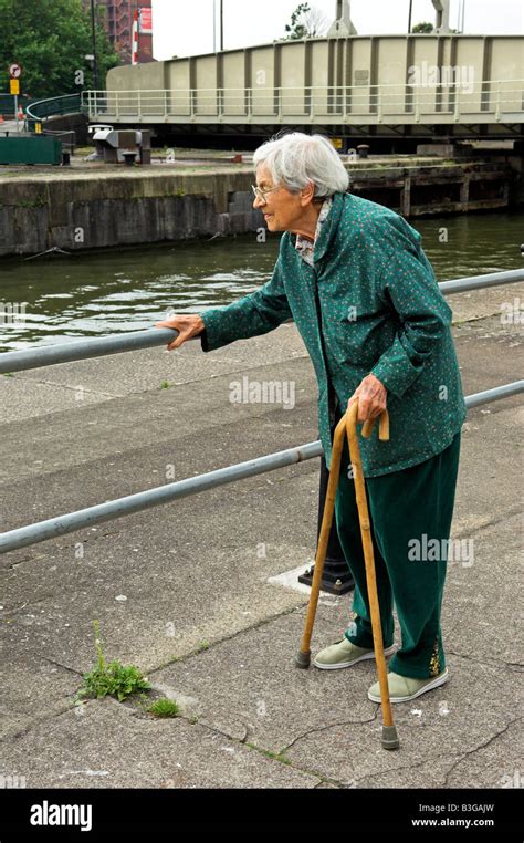 Active elderly English 92 year old woman holding two canes and holding railing while walking ...