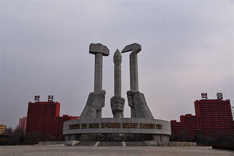 the monument is in front of two tall buildings with red balconies behind it