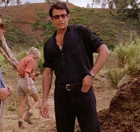 two men standing next to each other on a dirt road with trees in the background