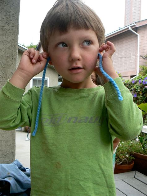 a young boy is holding his ears up