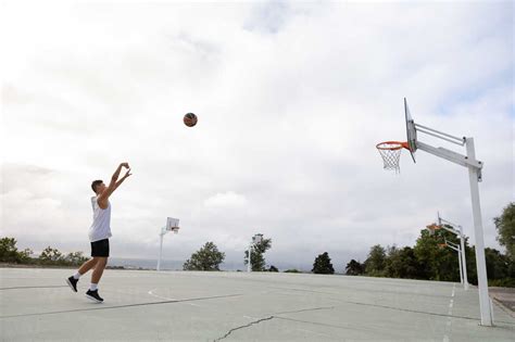 Male teenage basketball player throwing ball toward basketball hoop ...