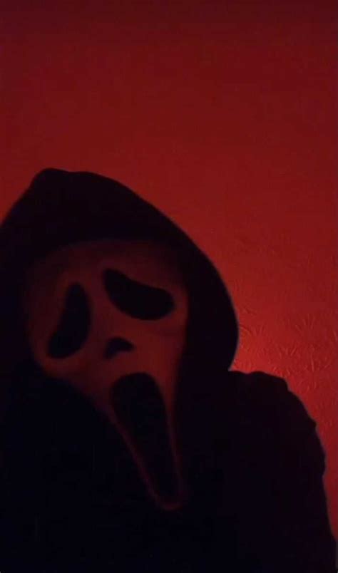 a person wearing a scary mask in front of a red wall