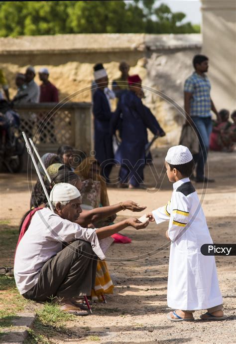 Image of Kid giving alms to the needy at Eid Prayer meet at Qutb Shahi Tomb-PN394190-Picxy