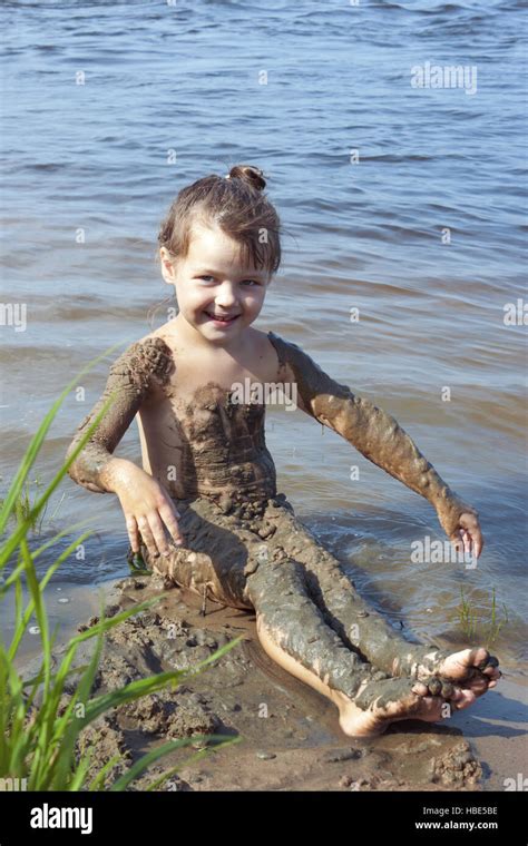 Baby girl in the mud on the river Stock Photo - Alamy