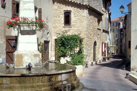 an old stone building with a fountain in the middle and flowers growing ...