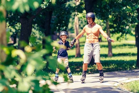 Premium Photo | Little boy learning roller skating in park with his grandfather