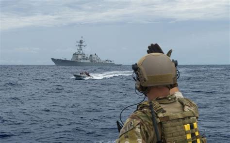 A U.S. Navy RHIB boat motors past the ‘Arleigh Burke’-class destroyer ...