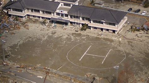 Aerial view of helicopter landing zone displaying "Thank You" message in mud after tsunami ...