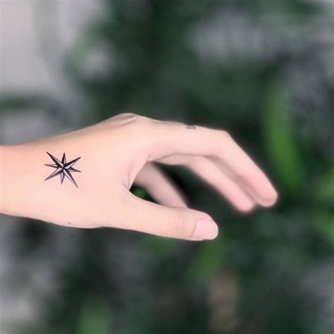 Compass rose tattoo on the left hand.